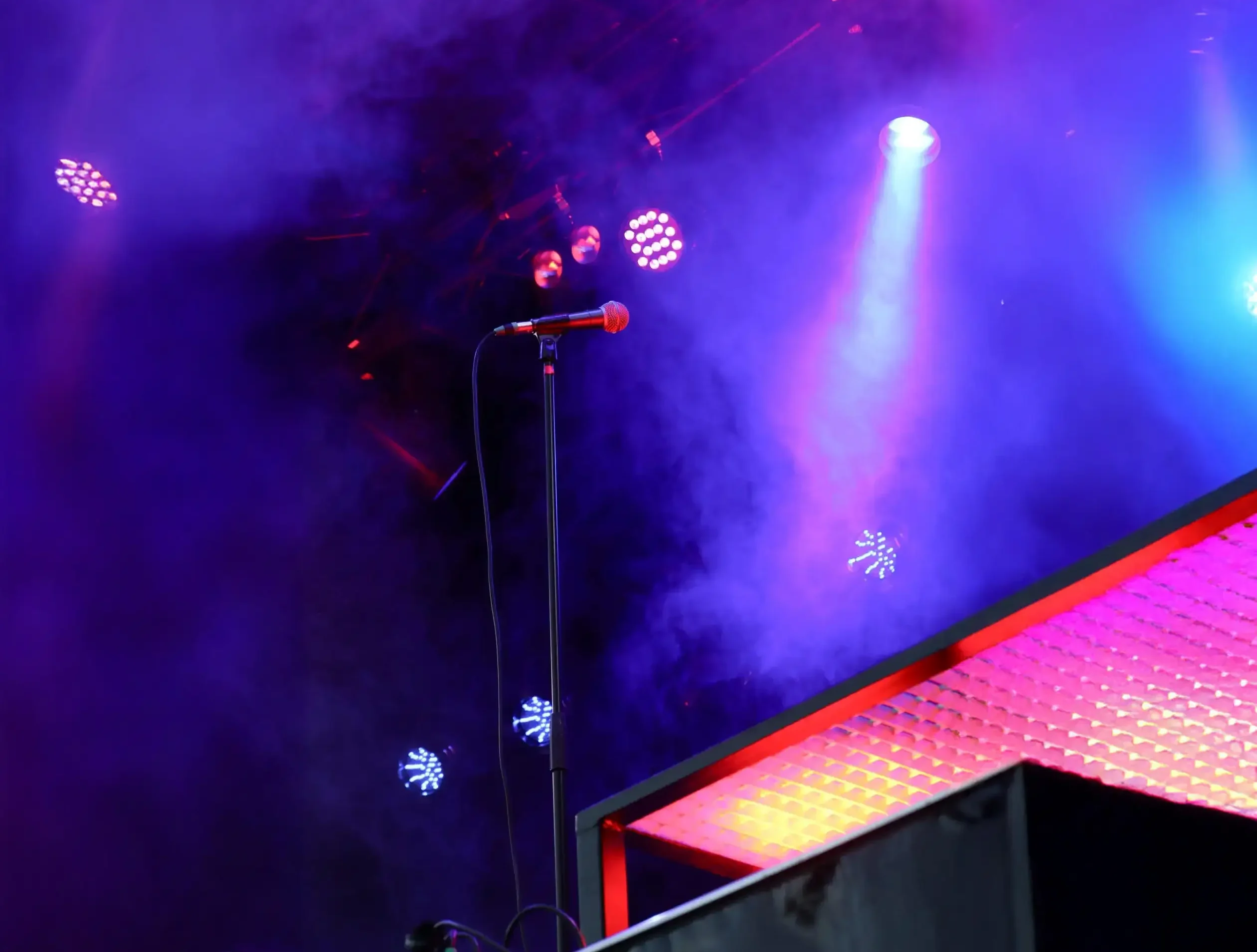 Microfoon op podium met dramatische paarse en blauwe belichting tijdens live concert, echt professionele geluidstechniek