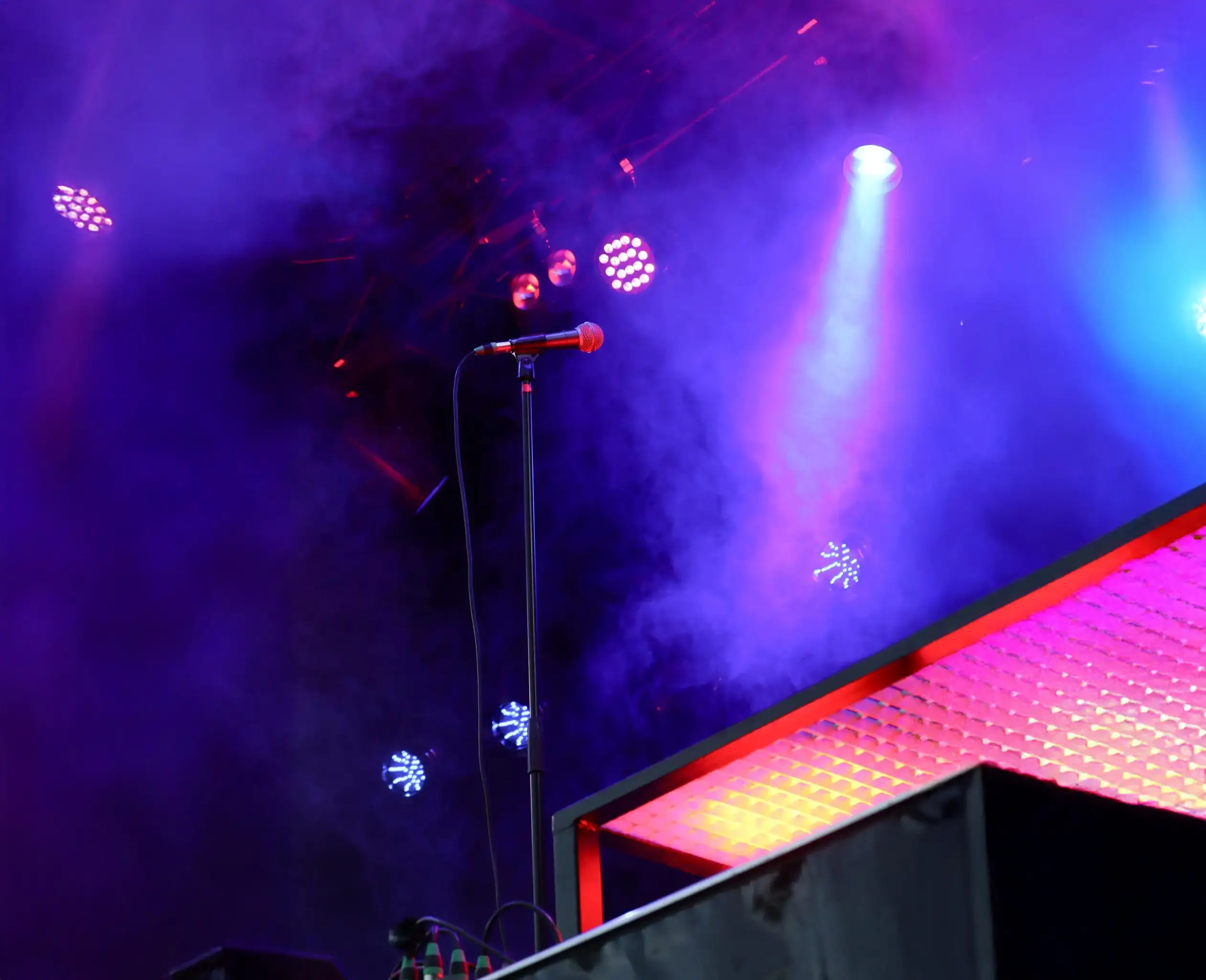 Microfoon op podium met dramatische paarse en blauwe belichting tijdens live concert